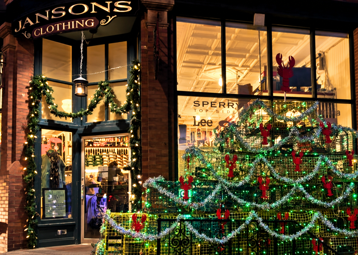 Janson’s Clothing storefront decorated with holiday lights and lobster traps in Boothbay Harbor.