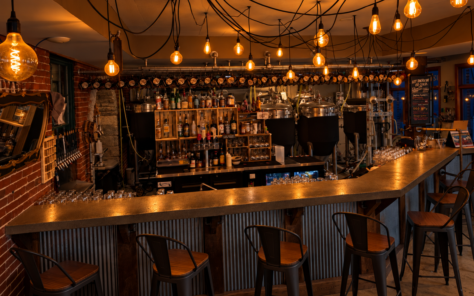 Warmly lit bar with Edison bulbs and brewing tanks at Footbridge Brewery & BBQ.
